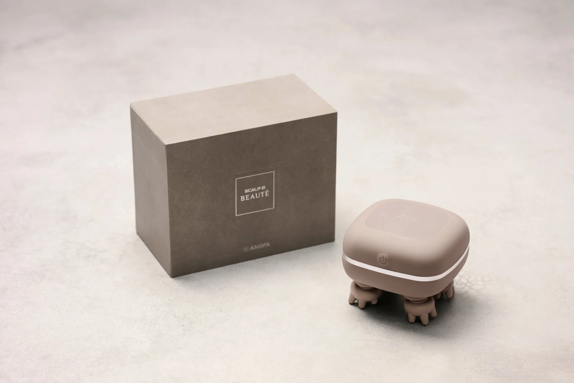 薄いベージュ色のスカルプケア用美容家電とそのパッケージが写っています。箱には「SCALP D BEAUTÉ」と「ANGFA」のロゴがあり、頭皮マッサージ器として使用される製品です。