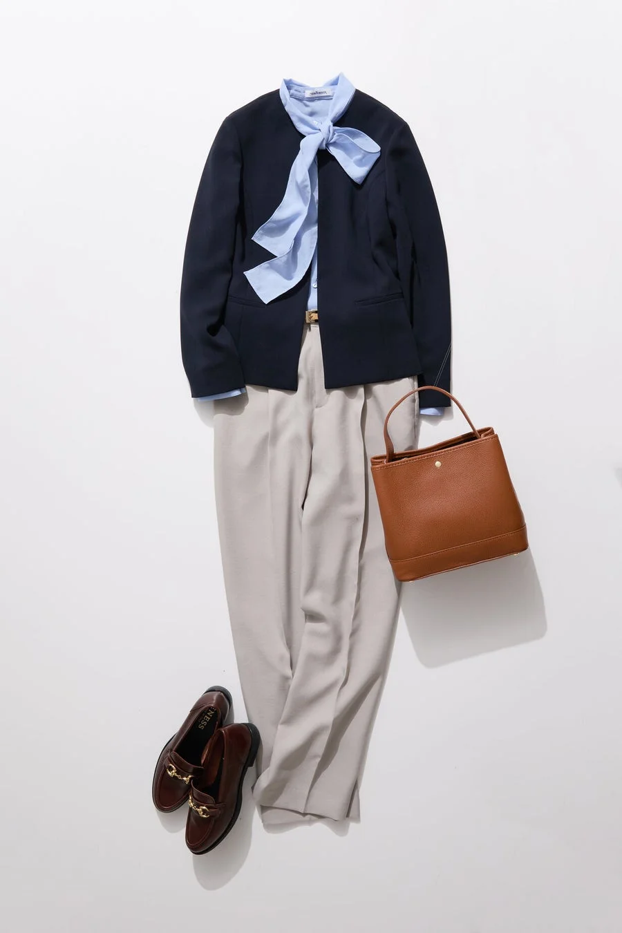 ネイビーのノーカラージャケットと水色のボウタイブラウス、ライトグレーのパンツを合わせたオフィスカジュアルなコーディネート