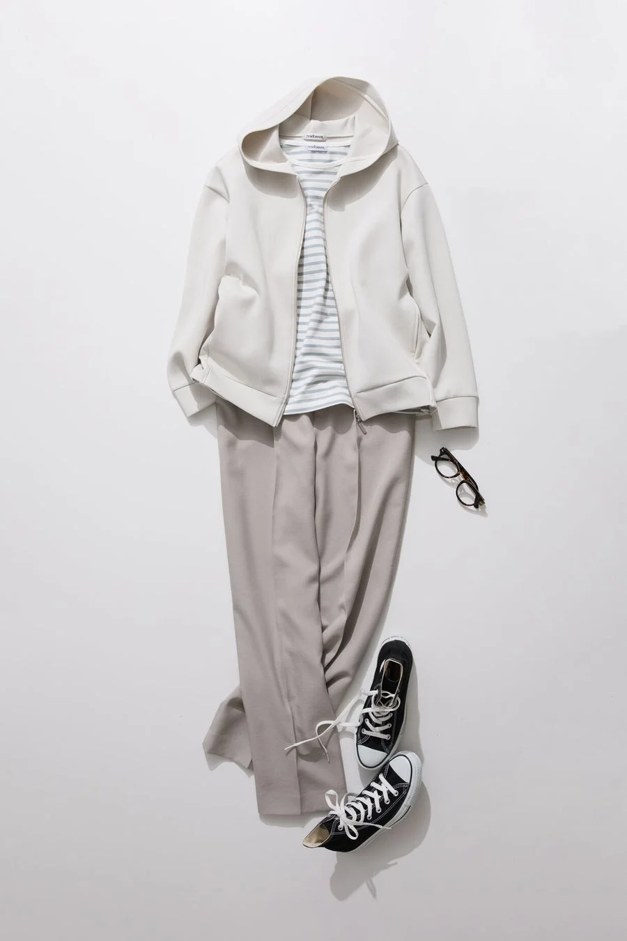 白いジップアップパーカー、ボーダーTシャツ、グレーのパンツ、黒いスニーカー、眼鏡を組み合わせたコーディネート