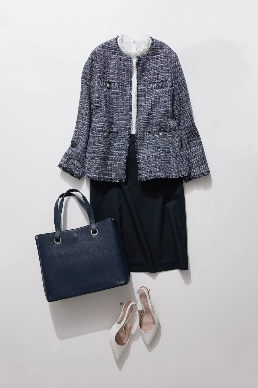 ネイビーのツイードジャケットとスカートに白いブラウスを合わせたオフィススタイル