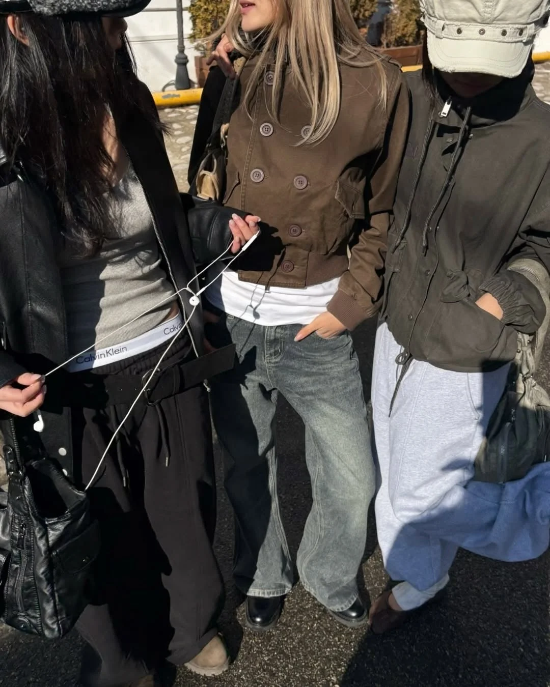 屋外で立つ3人の若者が、カジュアルでストリート感のあるファッションを楽しんでいます。